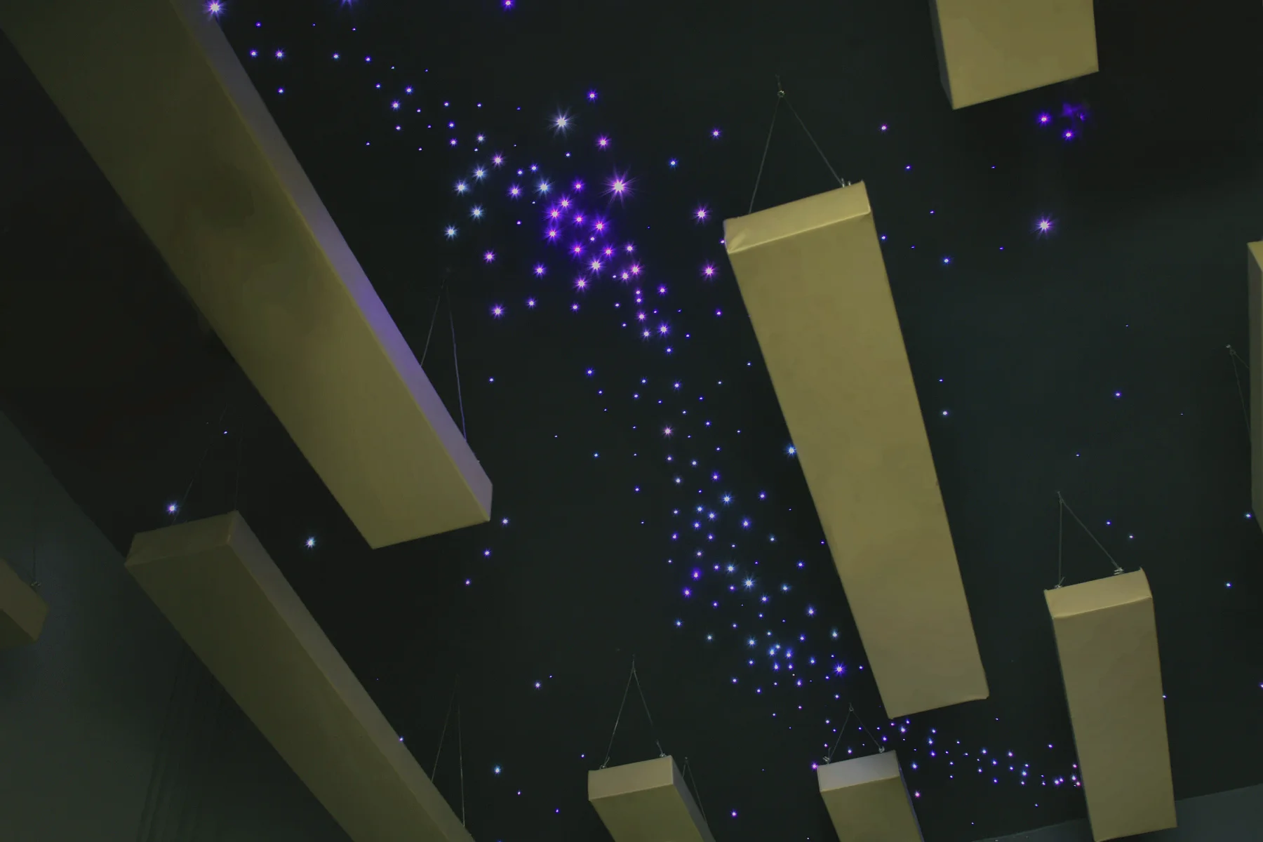 Stars drawn in light across the dark ceiling, with panels hung below.