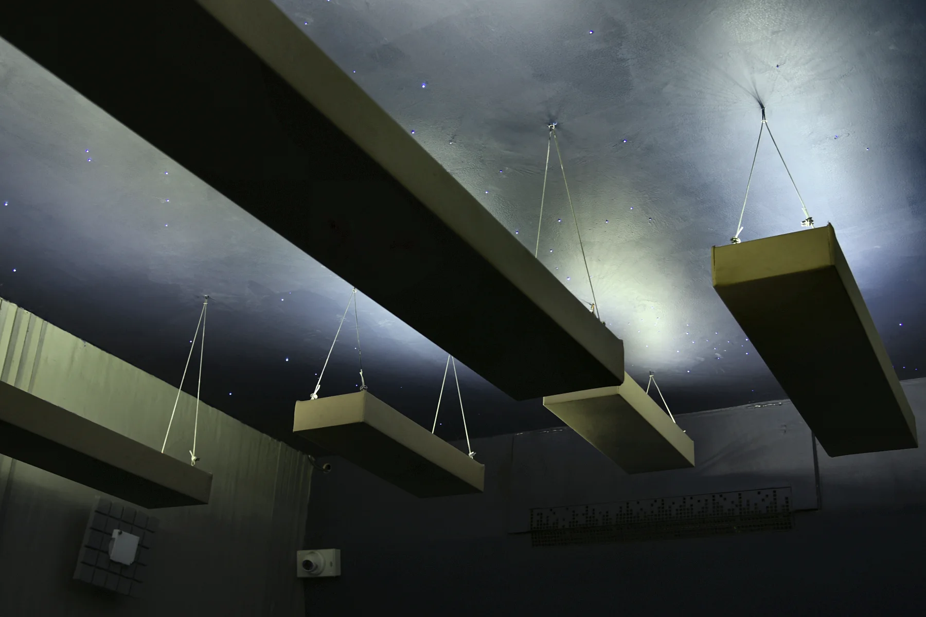 Panels suspended on thin wires, under a ceiling of fibre-optic stars.