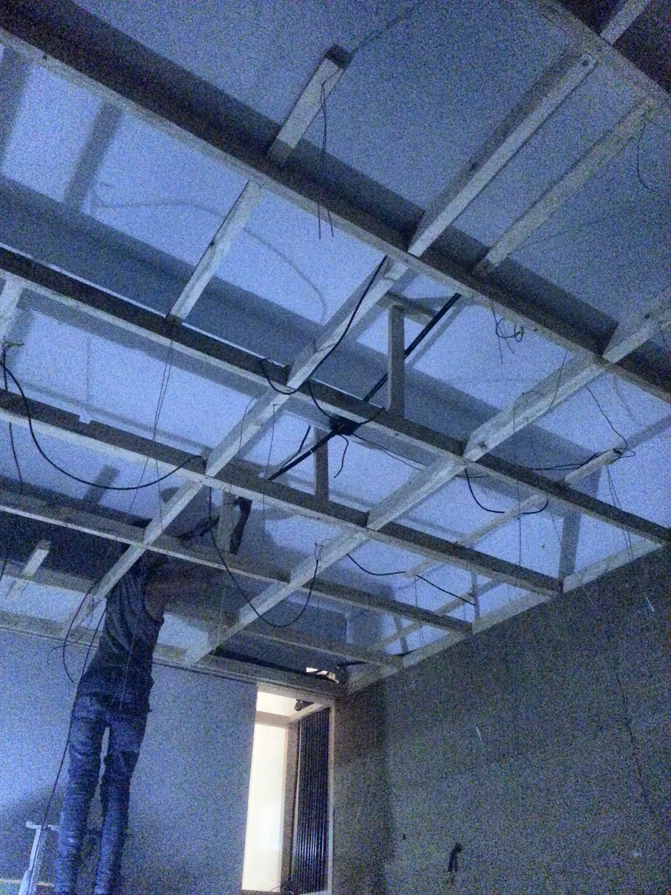 Above the room, a timber frame for the ceiling, with the wiring laid in before it closes.
