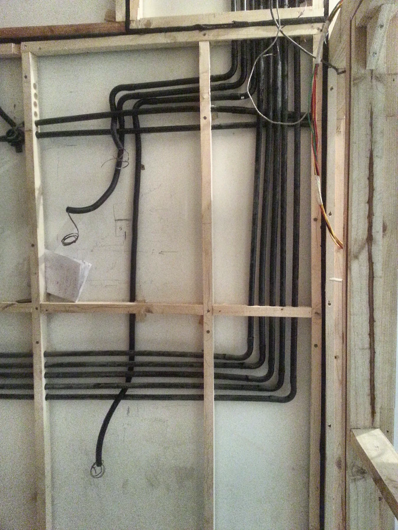 Inside a wall: a timber frame with every conduit laid in before the cladding goes on.