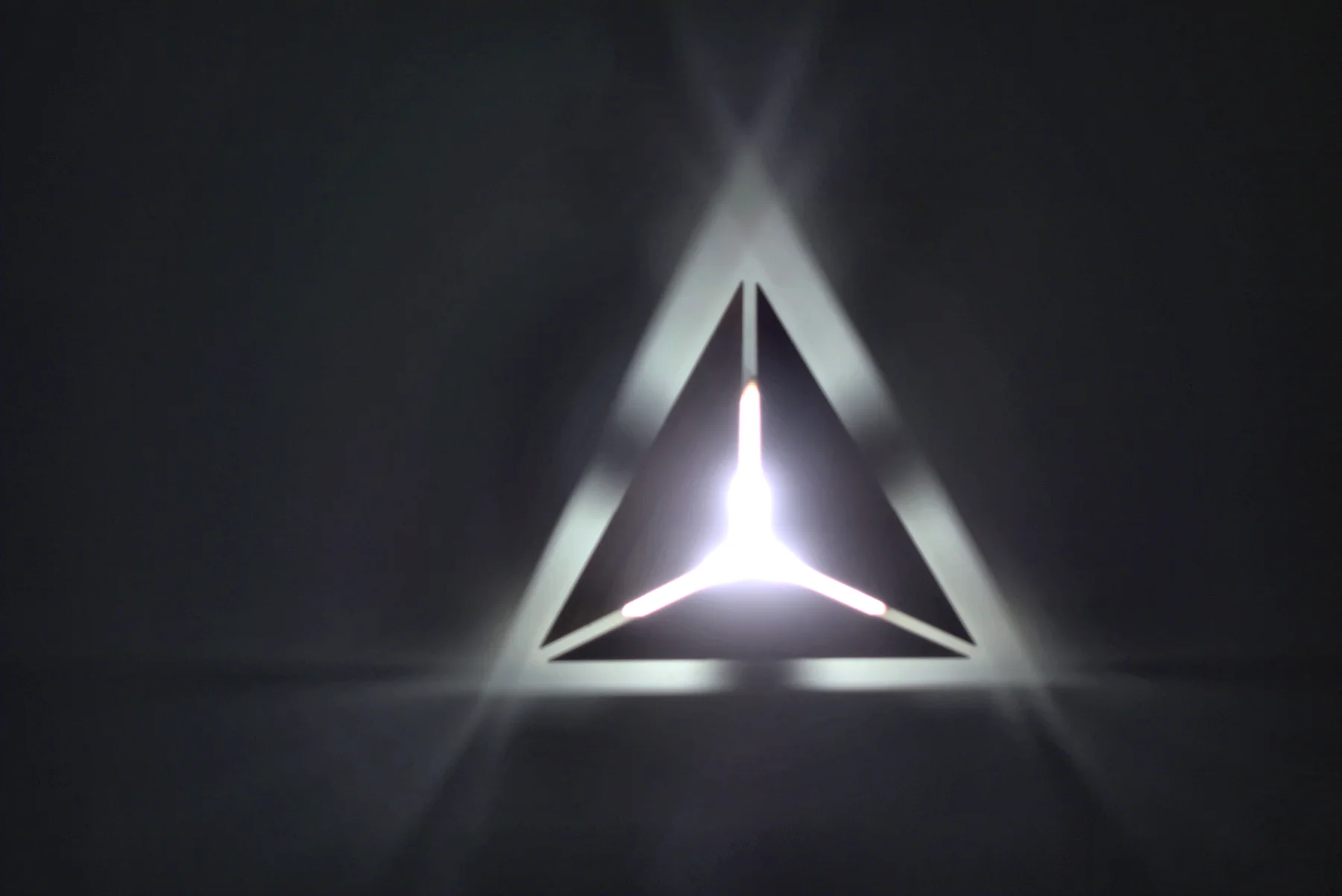The triangle light up close: a lit triangle cut into the wall with a three-armed light inside.