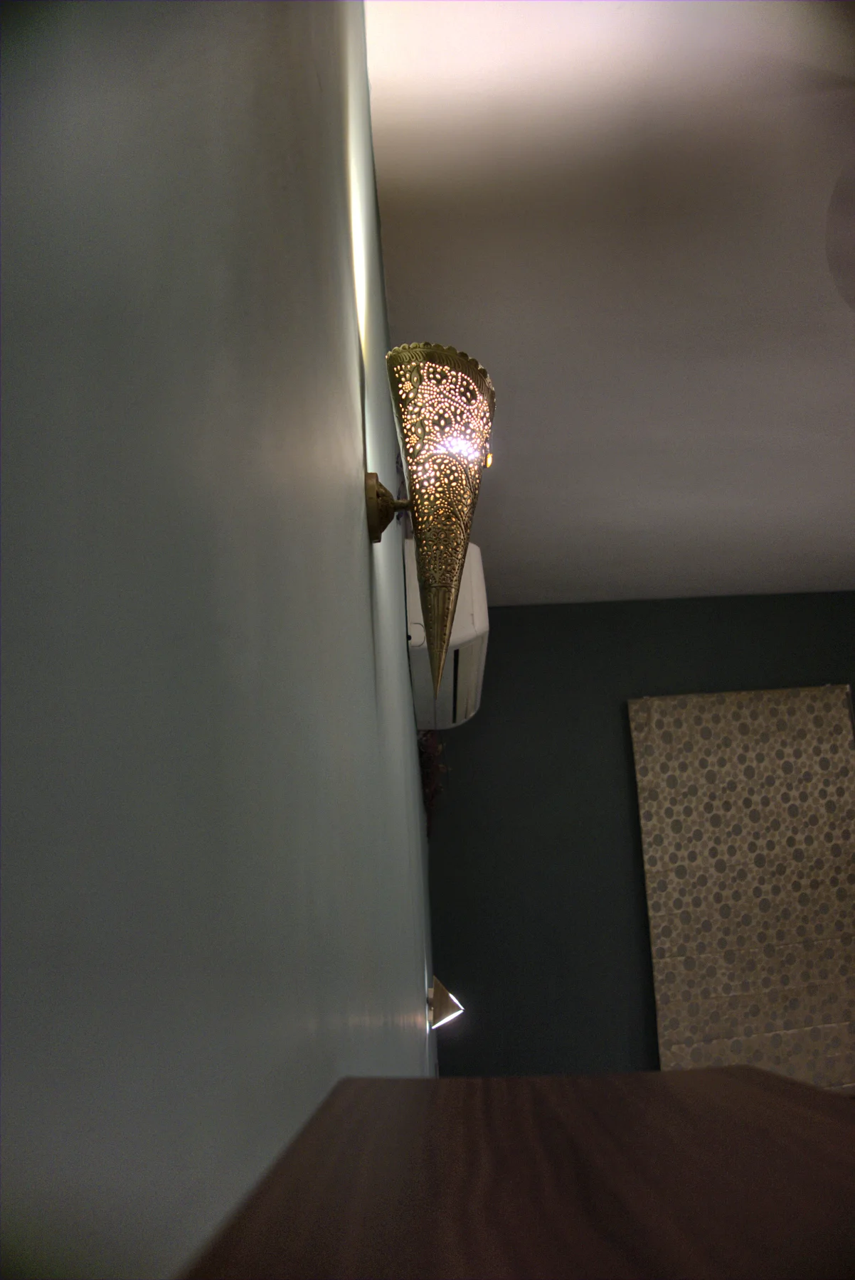 A hand-made wall lamp glowing in a corner of the green room.